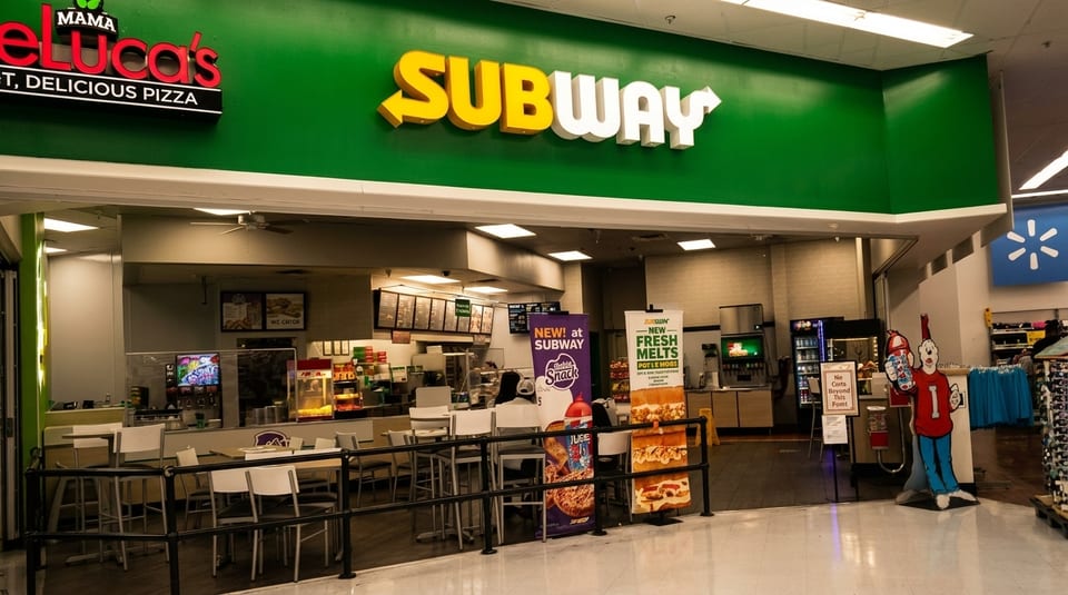 The entrance to a Subway restaurant, with a Mama DeLuca's Pizza sign visible on the left.